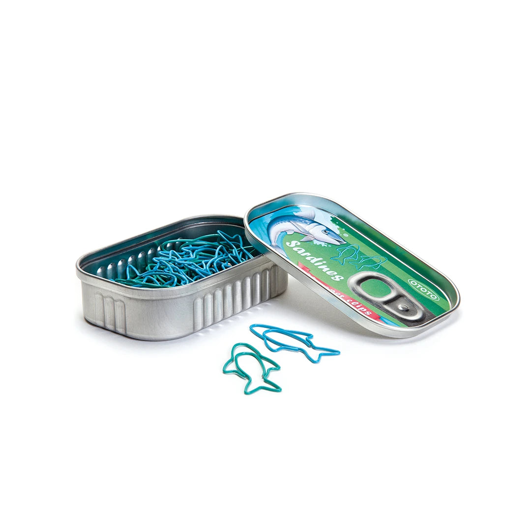 OTOTO Sardine Tin with gold paper clips shaped like blue fish spilling out.