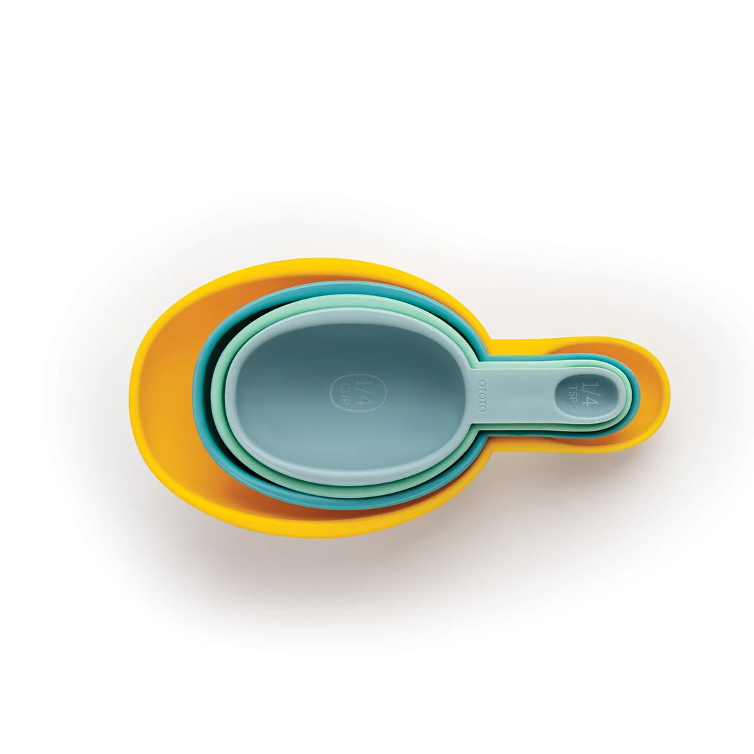 Shellys stacked, multicolored measuring cups, from yellow to blue, elegantly nest on a white background.