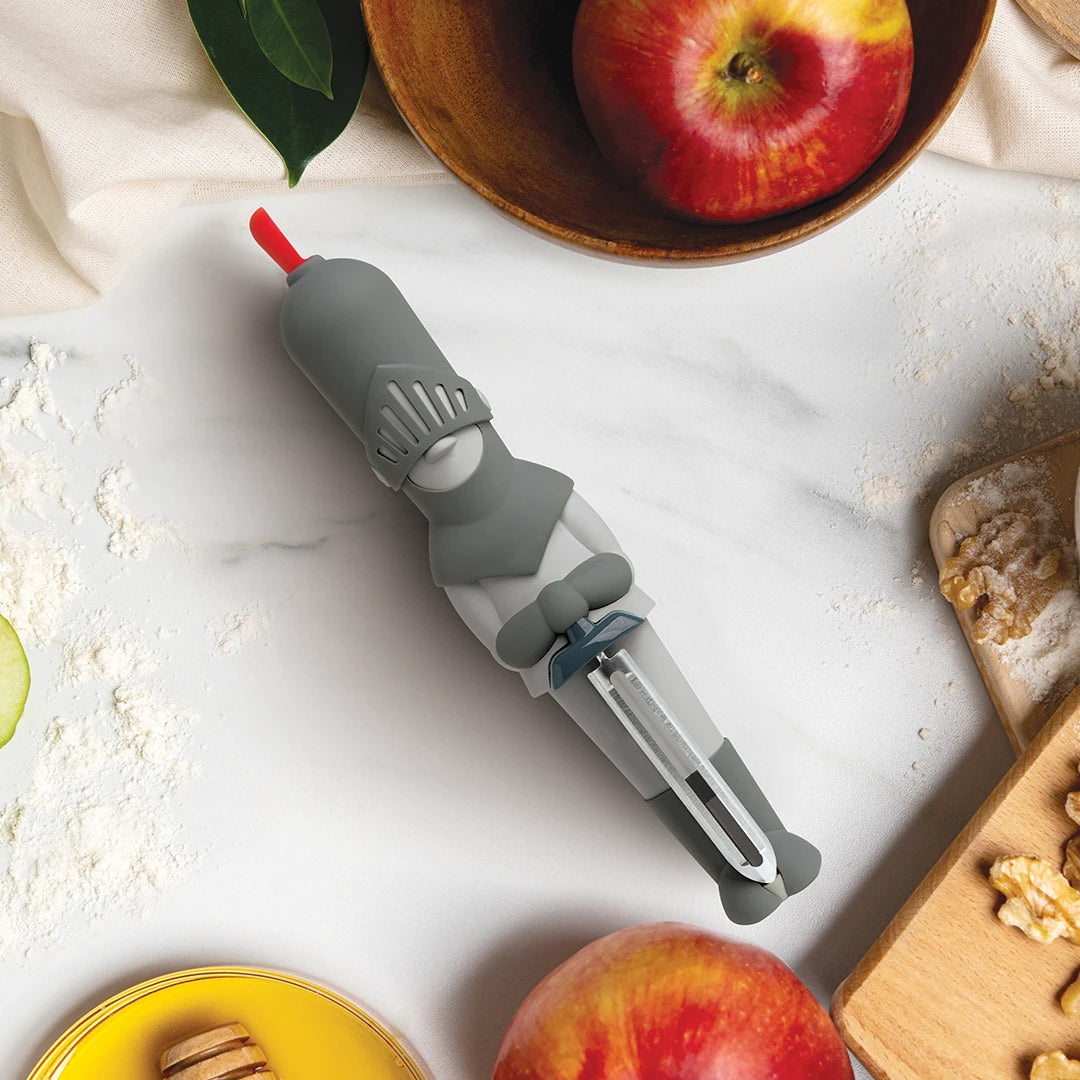 Sir Peels A-lot, the OTOTO knight-shaped peeler, sits among apples and baking ingredients on the counter.