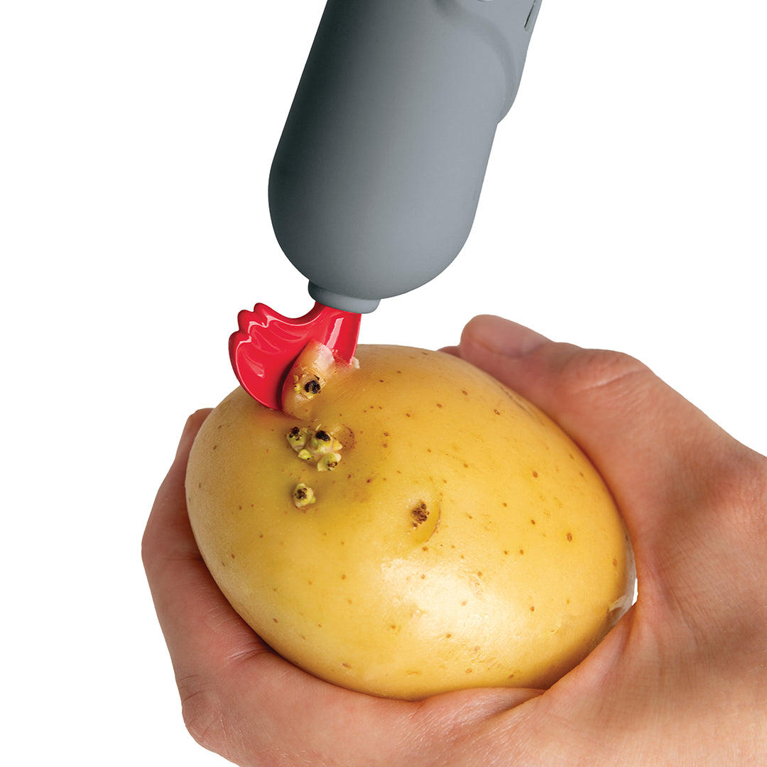 Hand using the Sir Peels A-lot to expertly remove eyes from a potato.