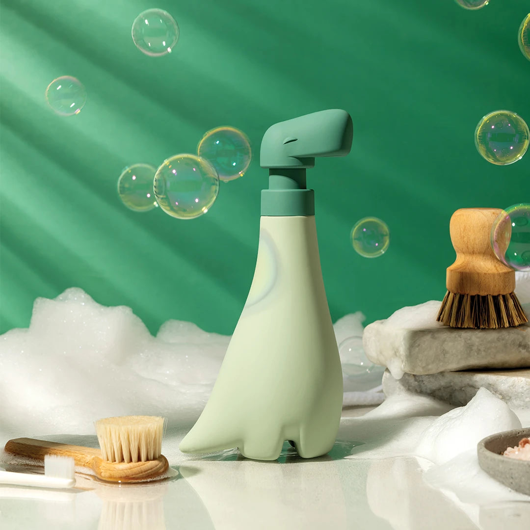 Soapasaurous soap dispenser features bubbles and brushes against a playful green background.