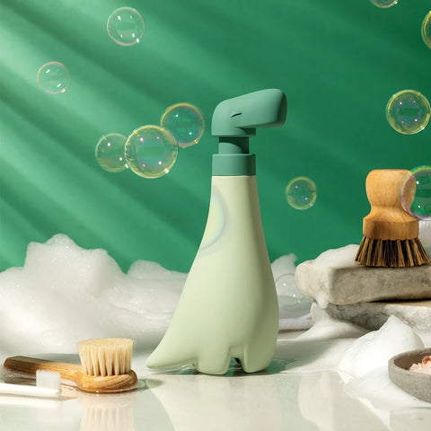 Soapasaurous soap dispenser features bubbles and brushes against a playful green background.