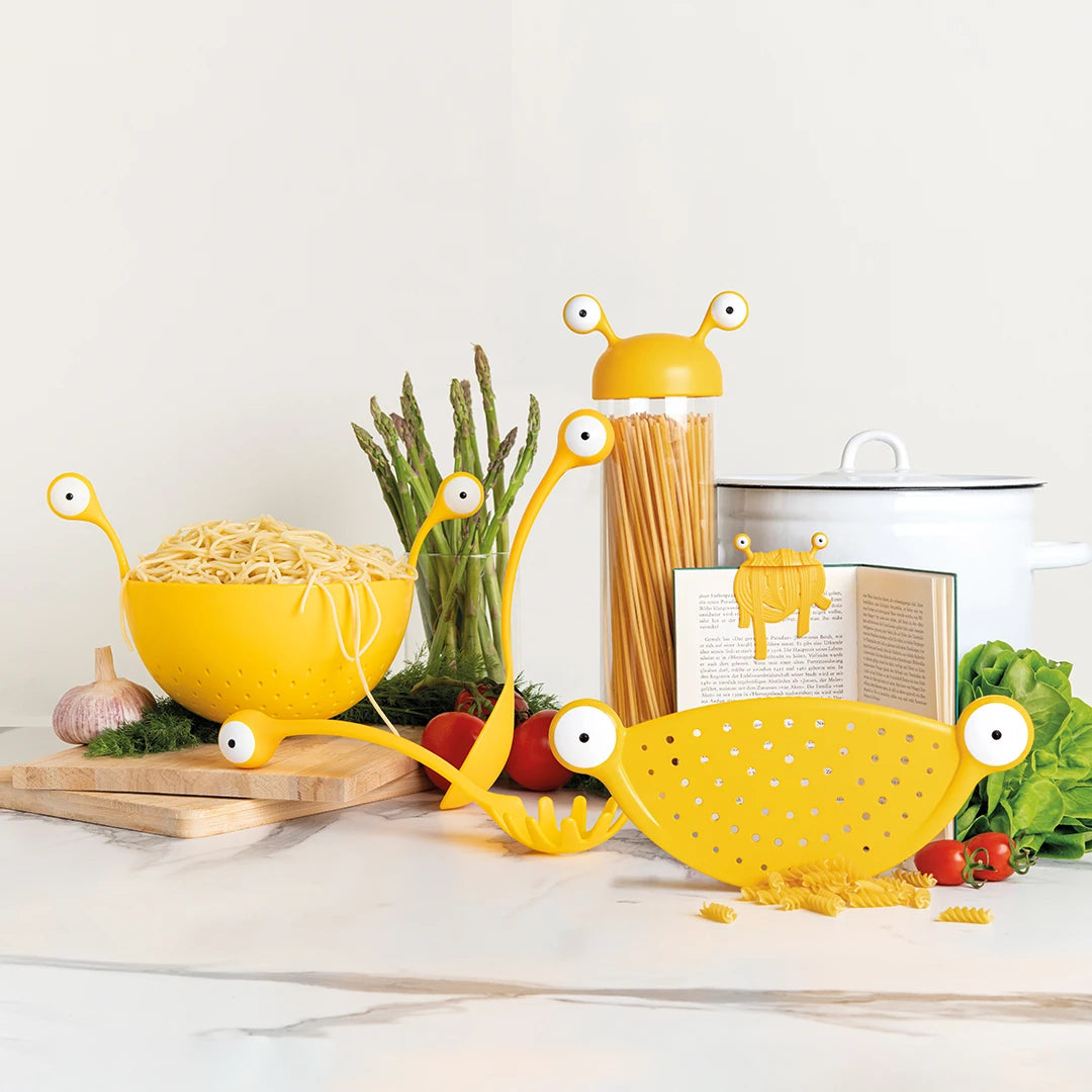 Spaghetti Monster utensils with googly eyes, arranged for pasta prep with tomatoes and greens.