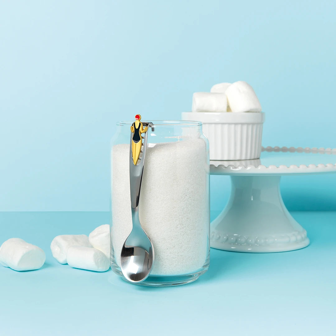 A Splash spoon hooks onto a jar, featuring a tiny figure surrounded by marshmallows and dessert stand.