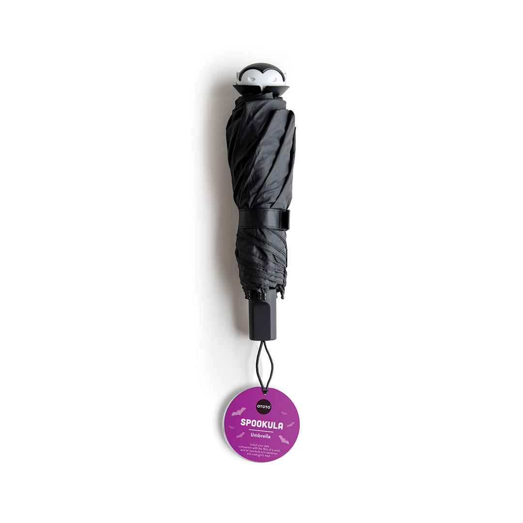 Black umbrella with a bat face handle and purple OTOTO tag, labeled Spookula.
