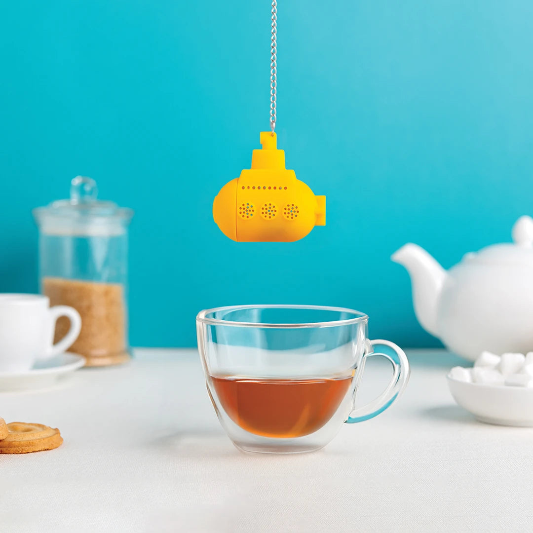 The Tea Sub infuser hovers over a tea-filled glass, set against a blue background.