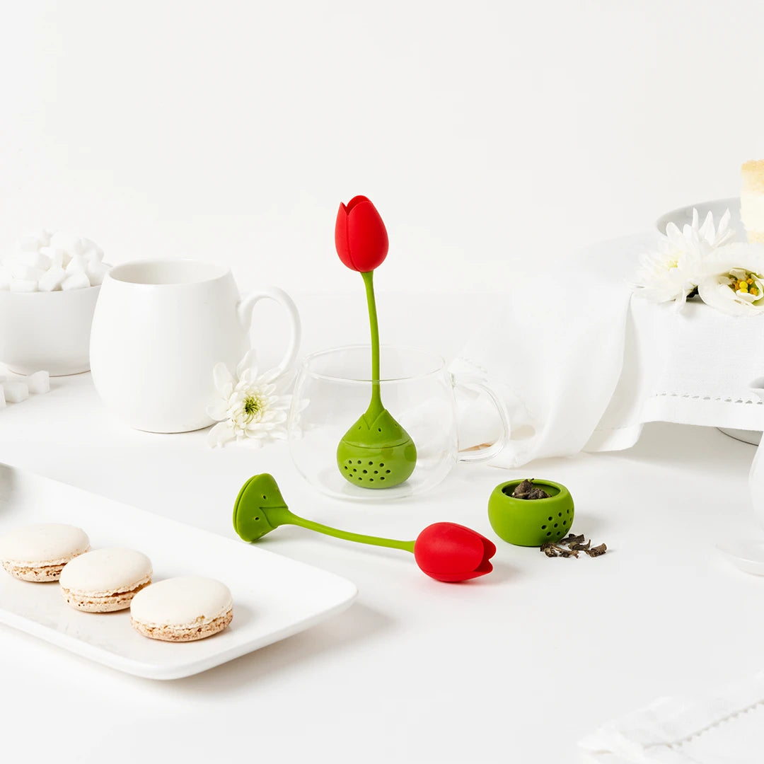 The OTOTO Tulip infusers with macarons adorn a table set with white crockery, flowers, and flavors.