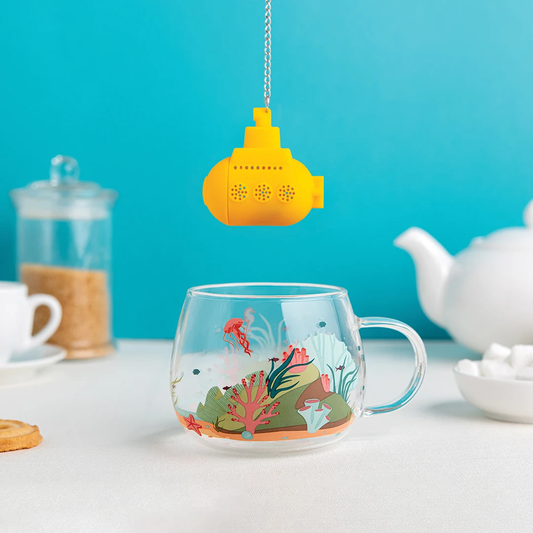 Adventurous Under the Tea diffuser in glass cup; teapot and sugar jar in background.