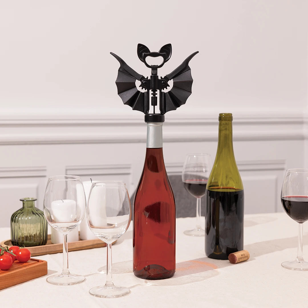 OTOTO Vino corkscrew shaped like a bat on a wine bottle, surrounded by glasses and another bottle.