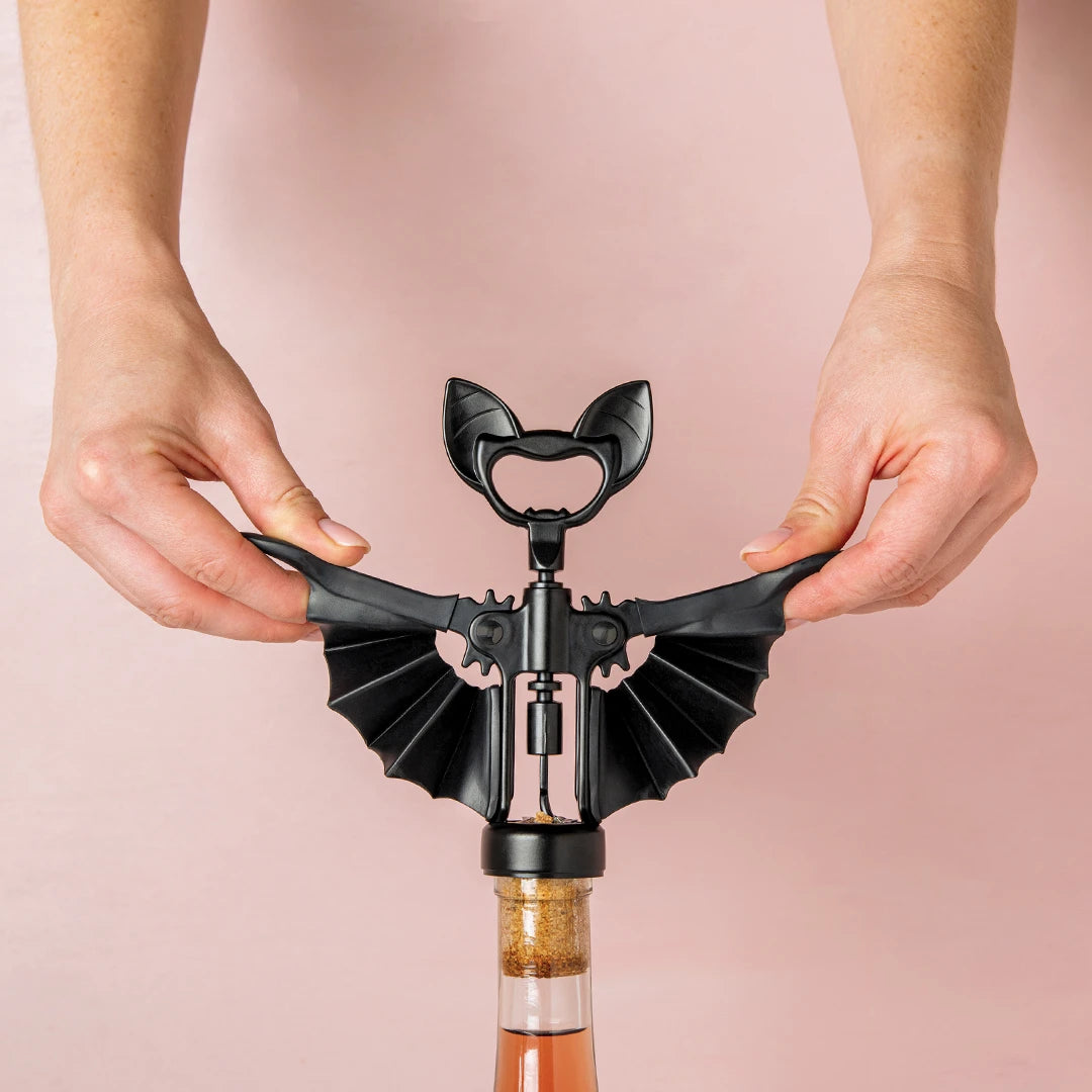 A person uses a Vino bat-shaped corkscrew by OTOTO to open a wine bottle.