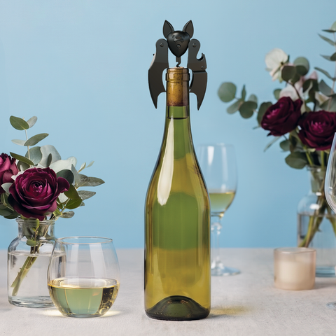 Mini Vino pairs with a bat-shaped corkscrew, flowers, and glasses for a whimsical wine scene.