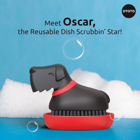 The OTOTO Oscar dog-shaped dish scrub brush rests on its red base with soap suds and bubbles.