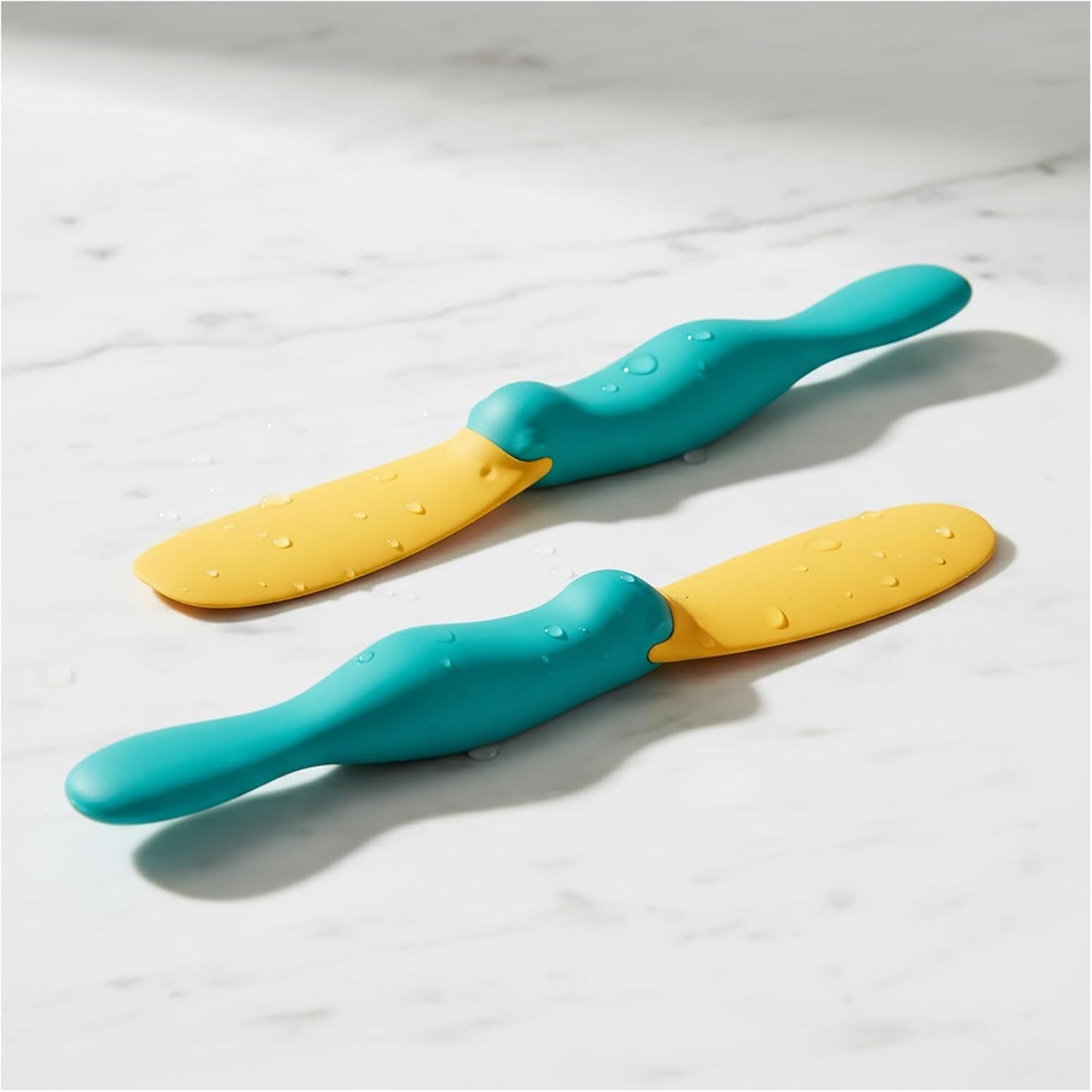 Two Splatypus butter spreaders from OTOTO are displayed on a marble surface.