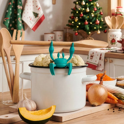 An OTOTO Aqua silicone utensil rest shaped like a crab sits festively on a pot in the kitchen.