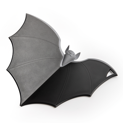Batty: A spooky-cute chopping board by OTOTO, bat-shaped with a cute face and gray-black wings.