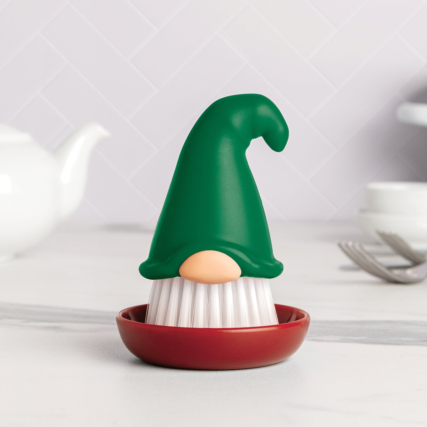 The Beardy dish brush makes kitchen chores fun, sitting in its red dish with a green hat.