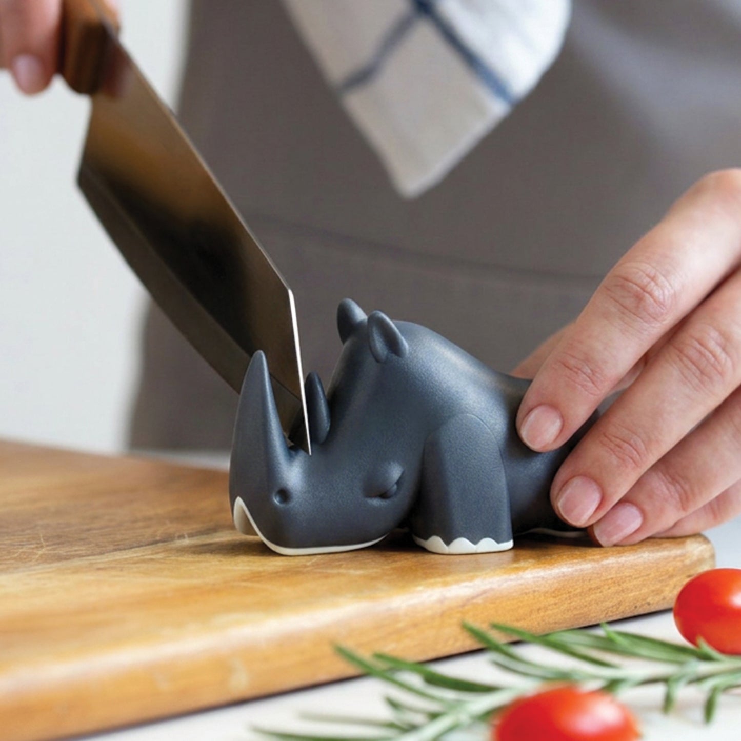 A person uses the Blade knife and an OTOTO rhino knife holder to safely cut vegetables on a board.
