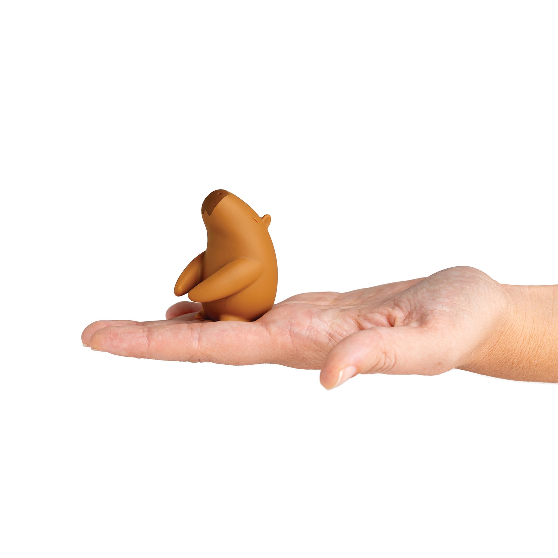 The Capybrush, a small brown capybara toothbrush holder, sits on an open palm.