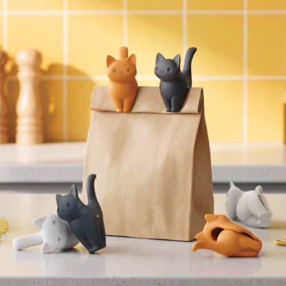 Four CatSnap clips, shaped like cats in orange, gray, and white, seal a bag in the kitchen.