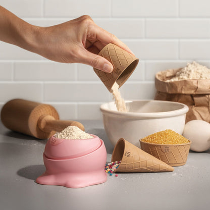 Flour is poured from a Coney measuring cup into a bowl, perfect for baking cookies.