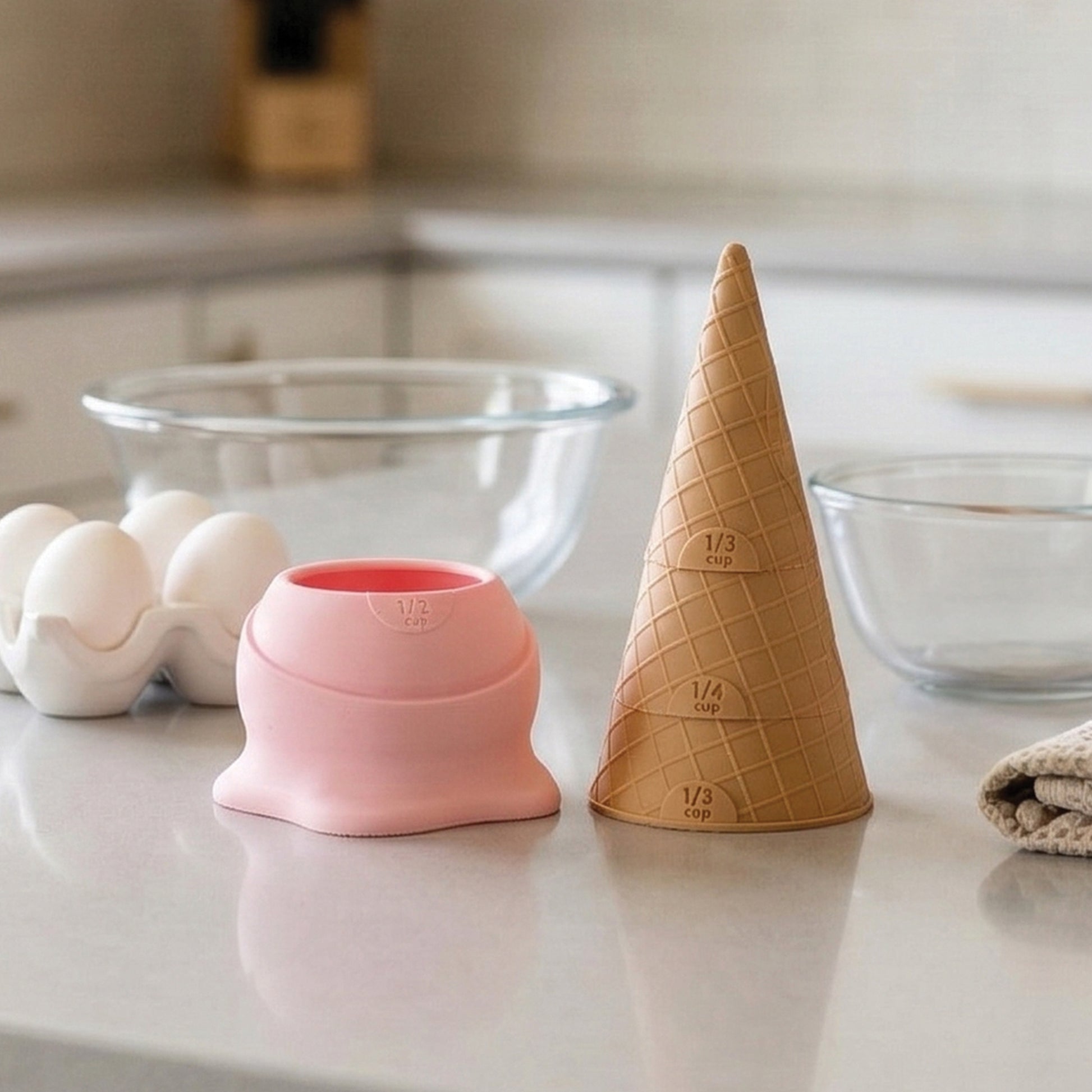 Two Coney measuring cups, ideal for baking or pancake batter, rest on a kitchen counter.