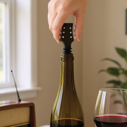 A hand places the Cork N' Roll wine stopper into a bottle next to a glass on the bar cart.