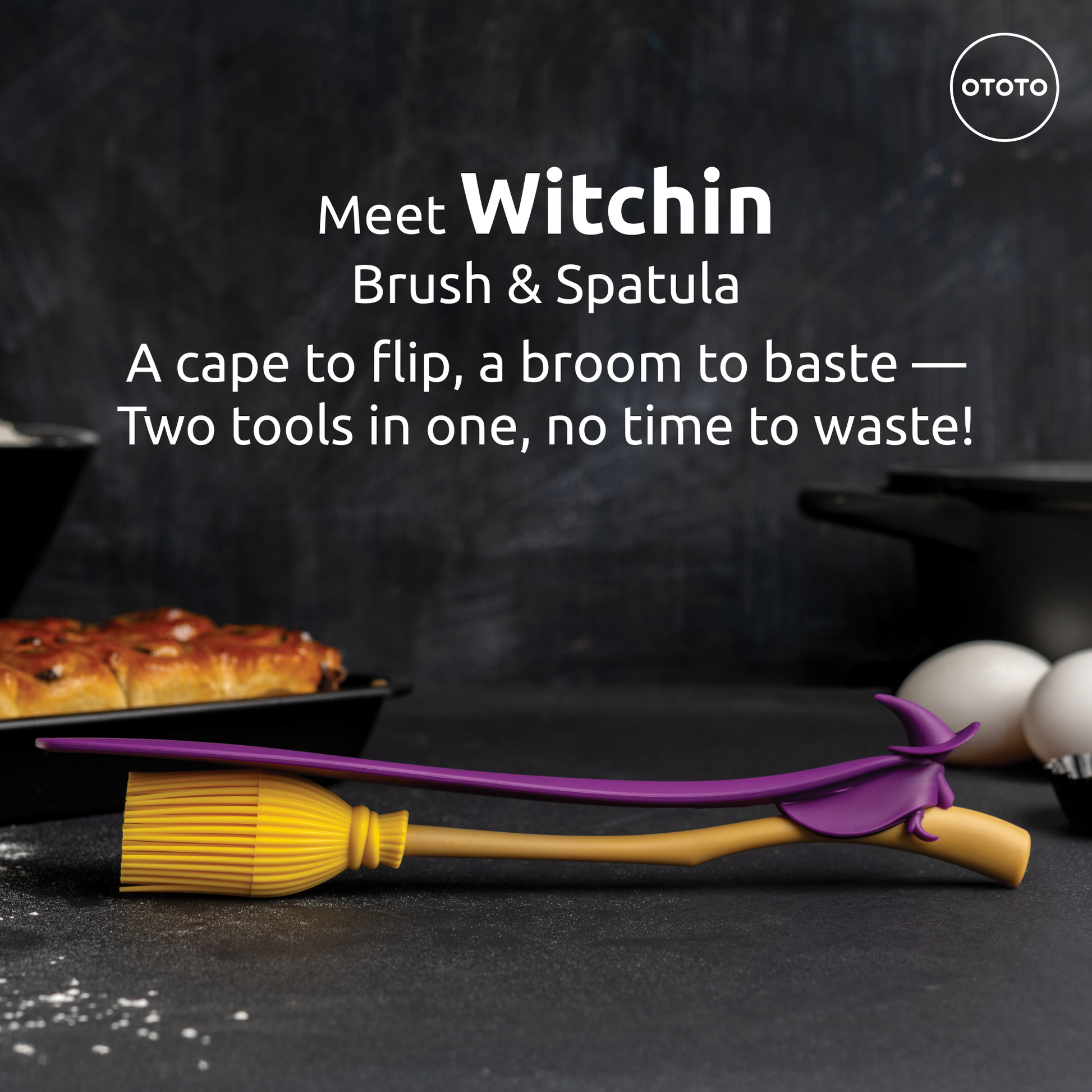 A Witchin yellow broom-shaped basting brush and heat-resistant spatula rest on a kitchen counter.