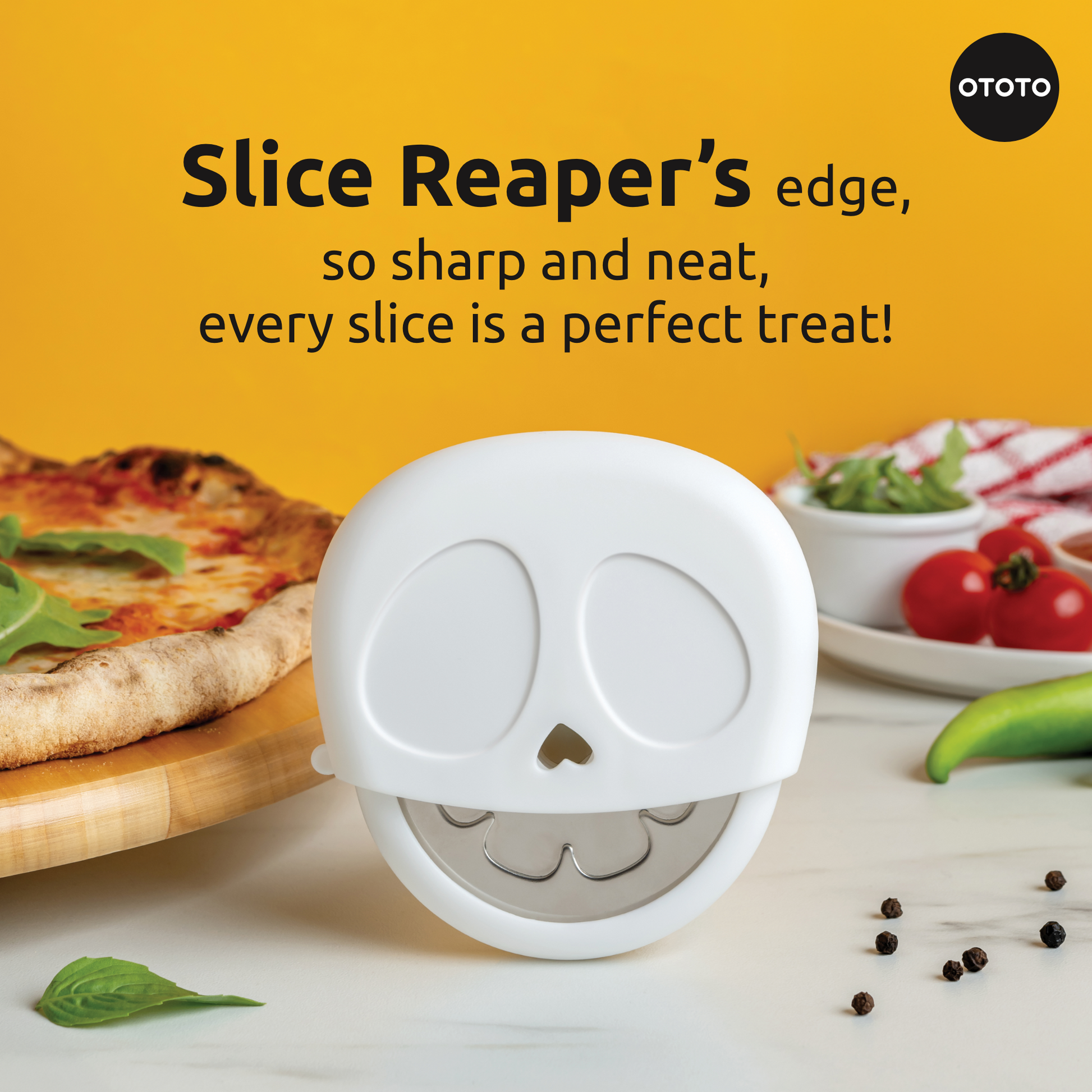 The Slice Reaper pizza cutter by OTOTO rests on a table with pizza, veggies, and spices nearby.