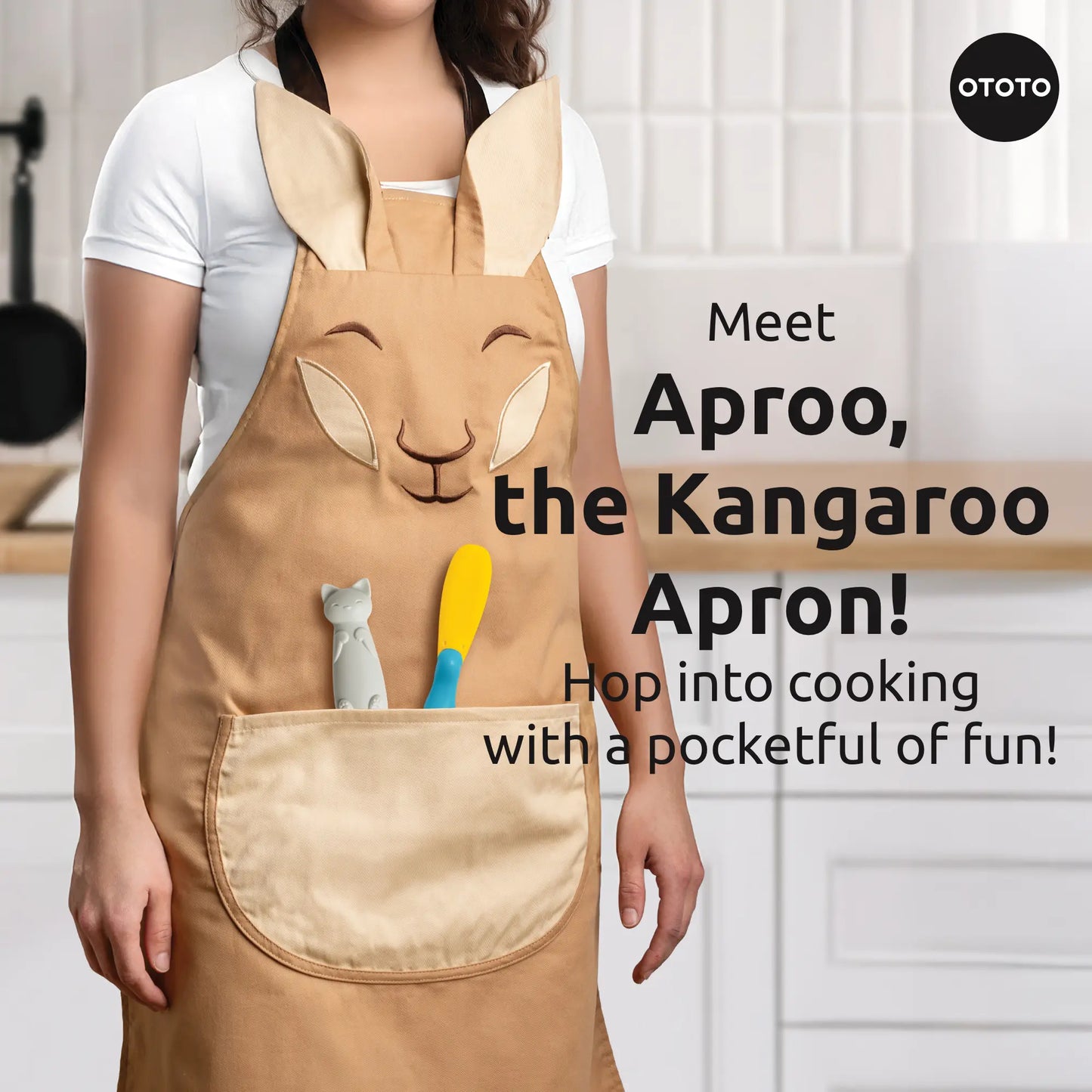 Someone wears the Aproo brown chef apron with a kangaroo face and pocket, holding utensils in a kitchen.