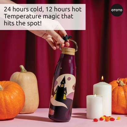 Hand holding the Boo!tle insulated water bottle with a spooky house, pumpkins, and Halloween candy.