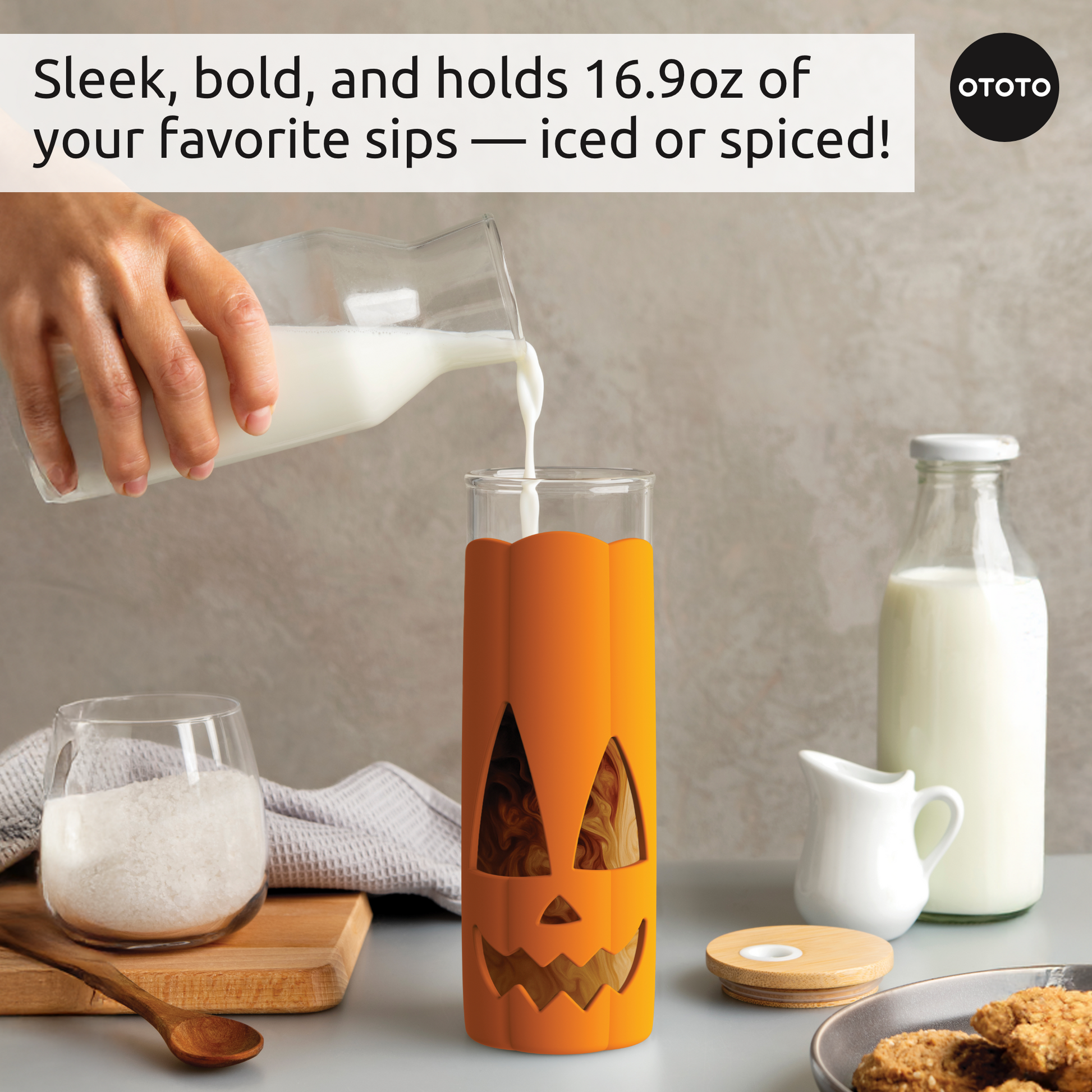 A hand pours milk into a Jack-o-Cup; milk, cookies, and a sugar bowl are nearby.