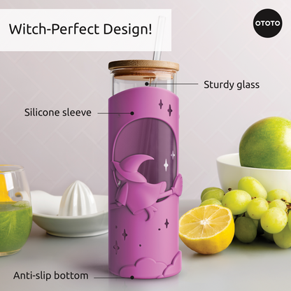 A Wicked Brew glass cup with a pink witch-themed sleeve sits on a counter surrounded by fruit.