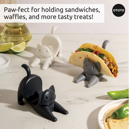 Three Catos taco holders display a taco, set in a kitchen with limes and peppers.