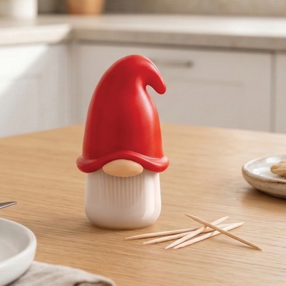 The Gnomeo toothpick dispenser by OTOTO, with a red hat, sits on a table next to toothpicks.