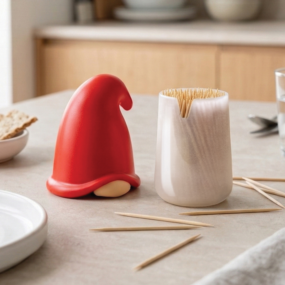 Gnomeo, a whimsical gnome toothpick dispenser by OTOTO, sits beside a white container on the table.