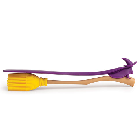 Witchin is a heat resistant silicone spatula shaped like a yellow broomstick with a purple handle.