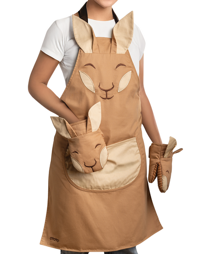 Someone wears the Aproo apron and oven mitts, both decorated with cute bunny faces and ears.