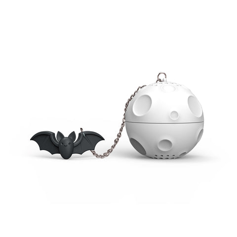 The OTOTO Moonlit is a small black bat keychain attached by a chain to a moon-shaped tea strainer.
