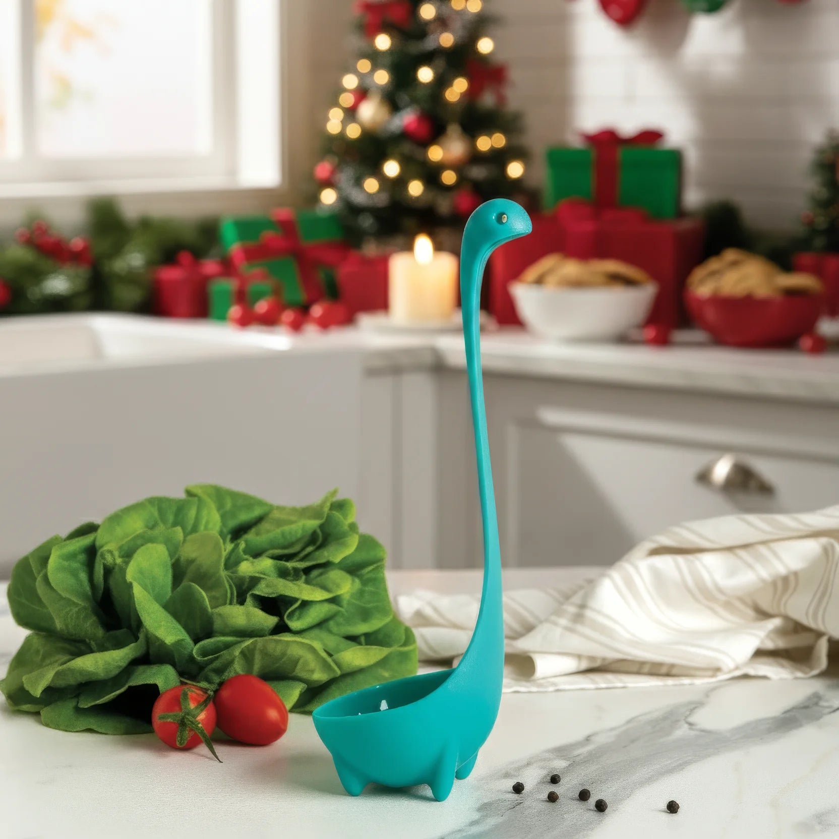 A Nessie ladle sits on a kitchen counter with holiday decor and gifts in the background.