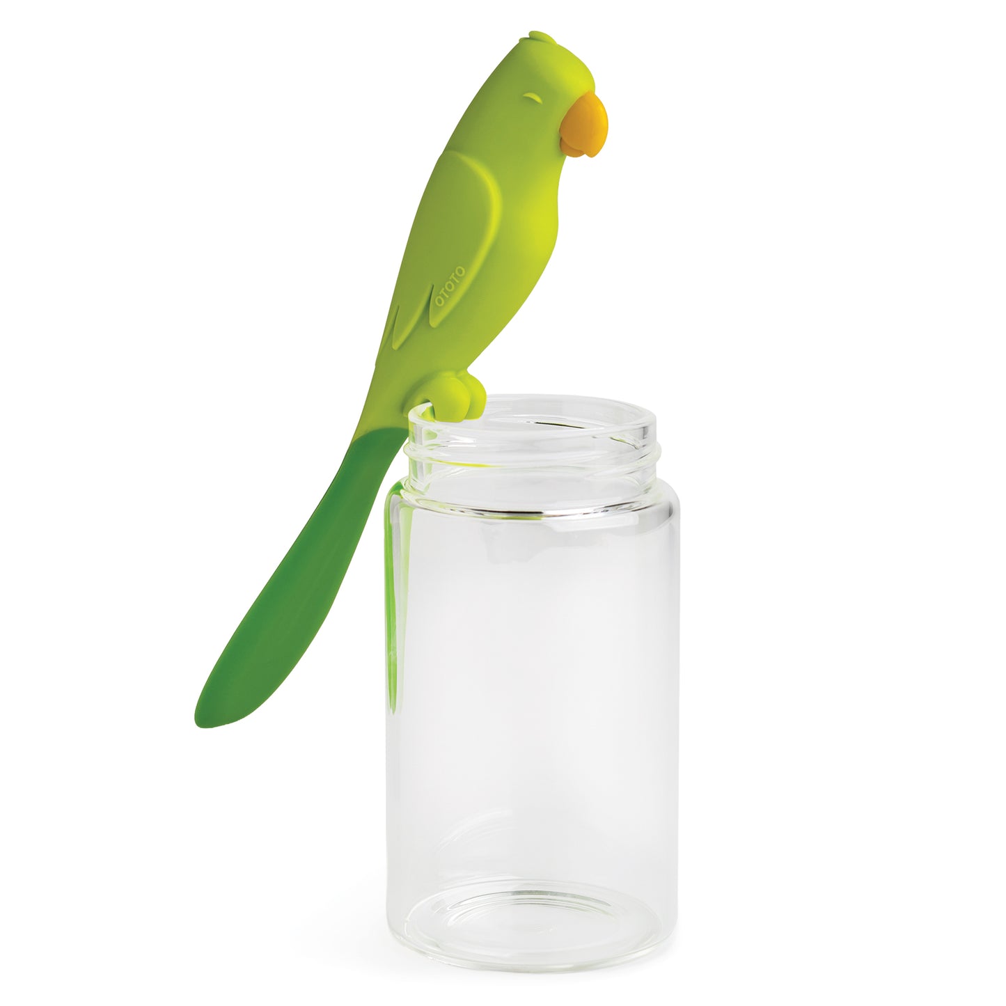 Parry, the green parrot-shaped silicone spatula by OTOTO, sits on a clear, empty glass jar.