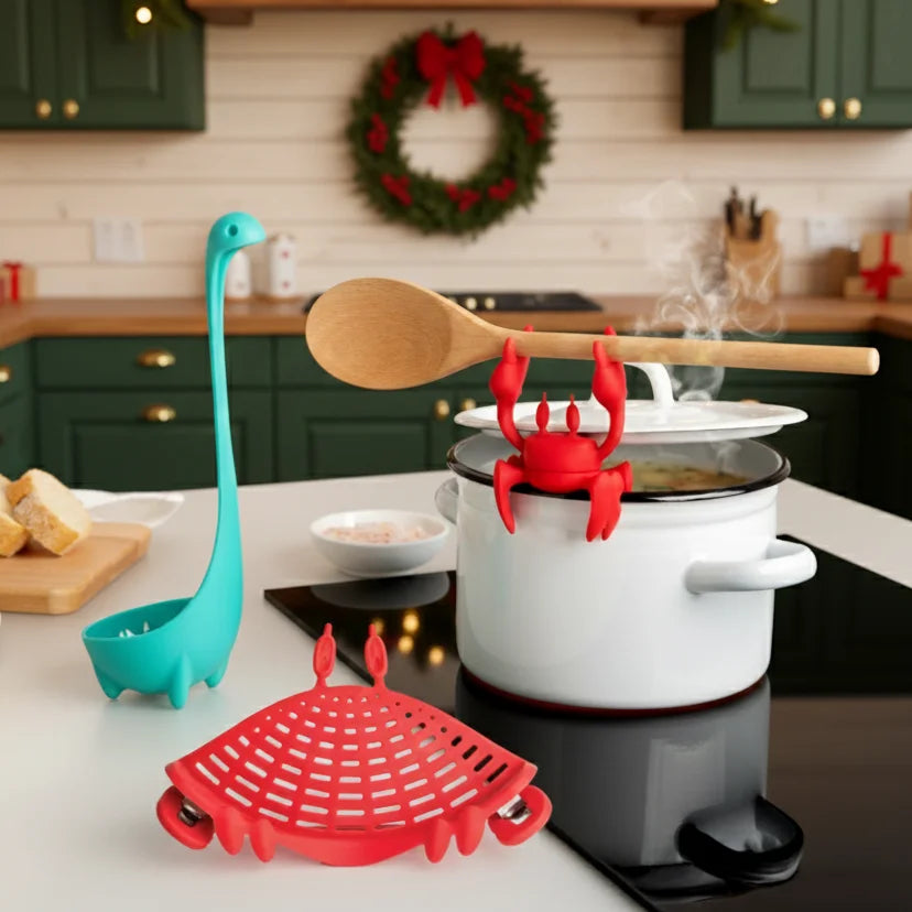 A Prep Pals crab utensil holder grips a pot in a festive kitchen with green cabinets.