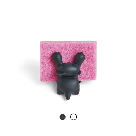A black bunny rests on a pink OTOTO Scrubby sponge, viewed from above.