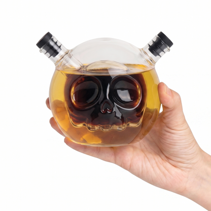 A hand holds a Skully-Olio, an OTOTO skull-shaped oil and vinegar dispenser with two spouts.