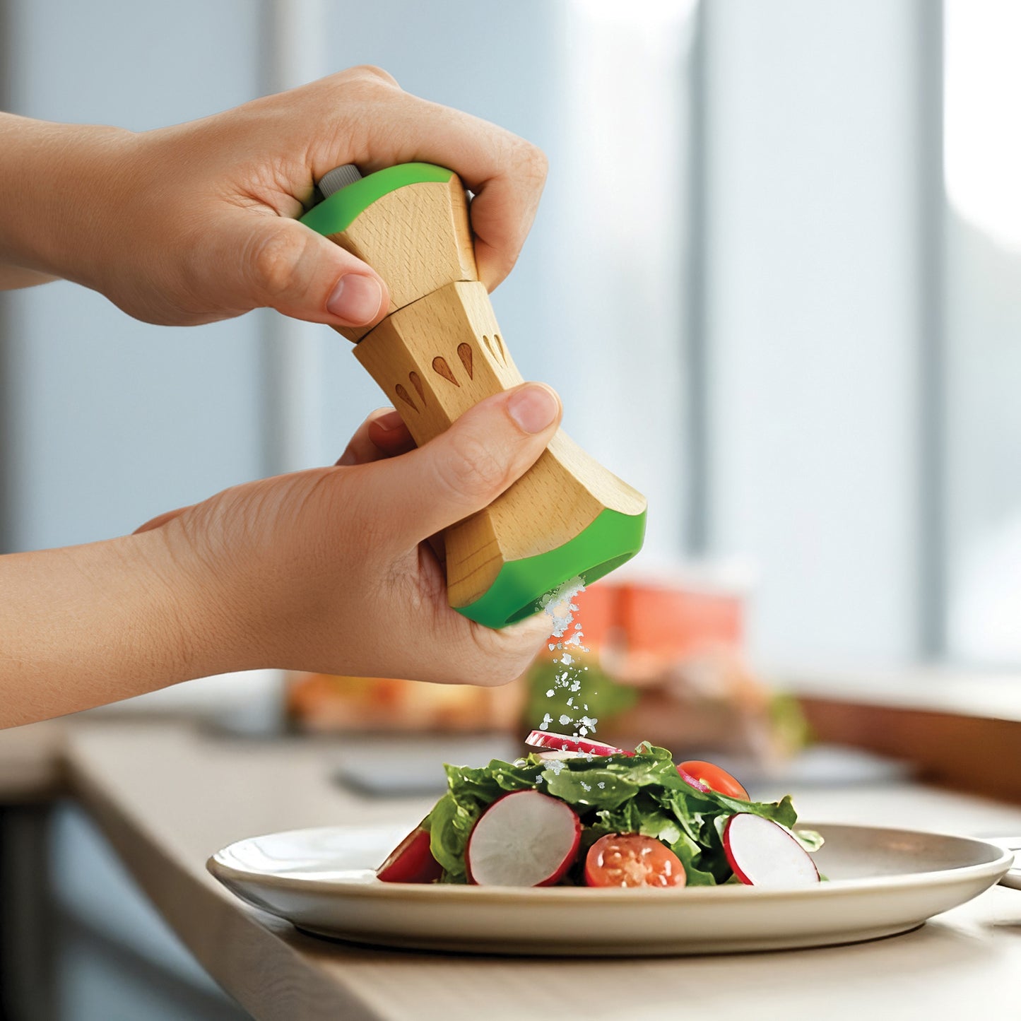 Someone seasons a fresh salad using the Twin Spice manual salt and pepper grinder set.