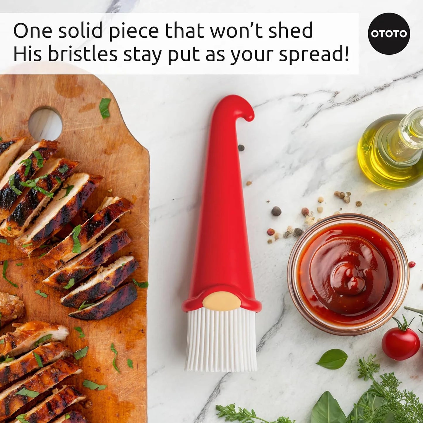 A red OTOTO Gnomeo pastry brush with sliced grilled chicken on a wooden board, herbs, oil, and sauce.