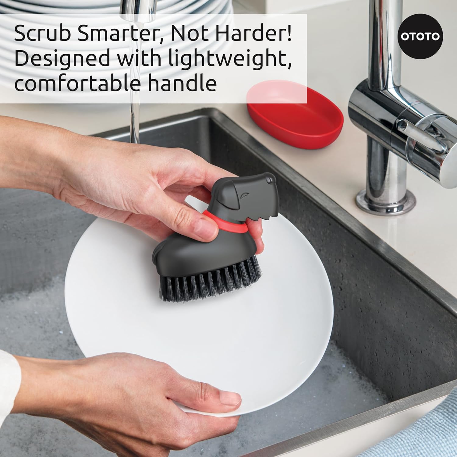 Person scrubbing a white plate by the sink with the Oscar Dish Brush.