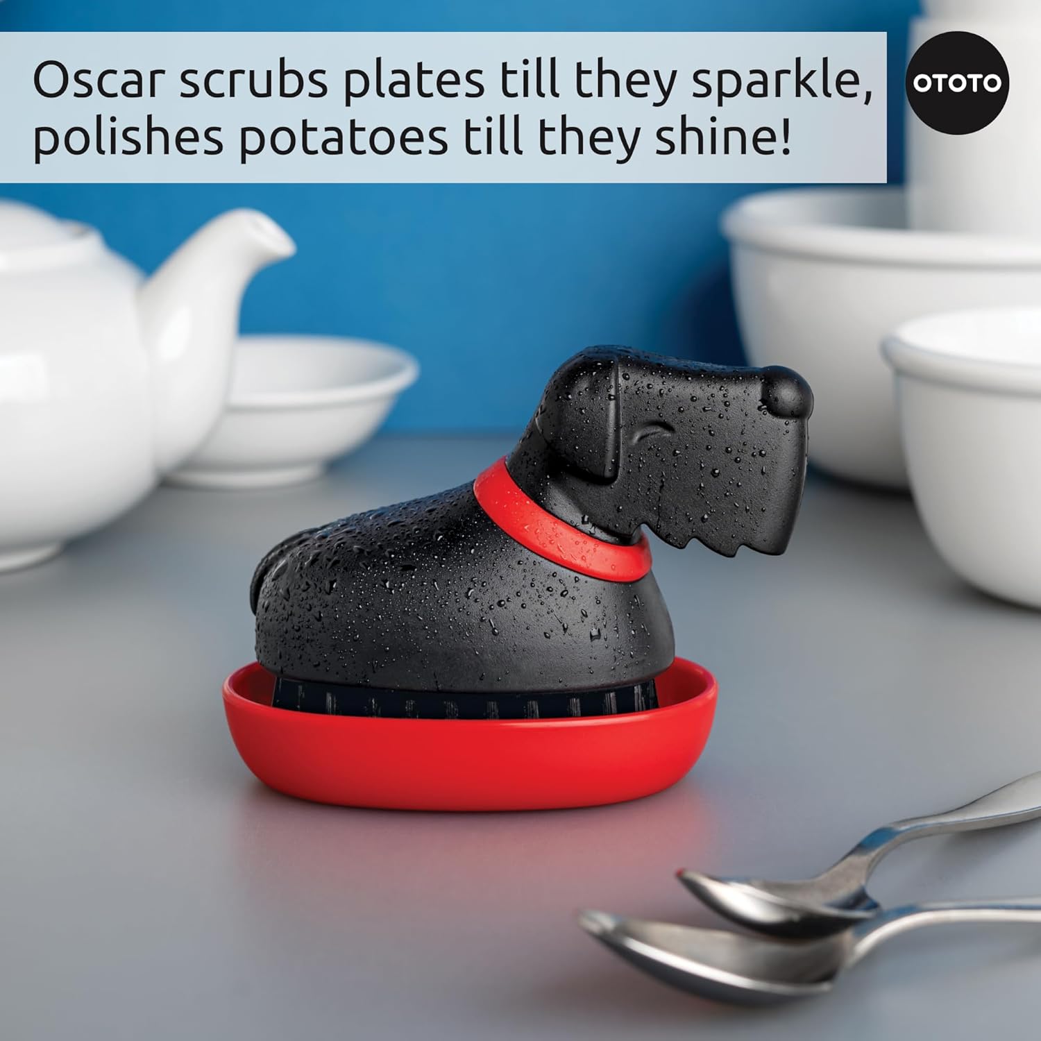 An Oscar Dish Brush by OTOTO with a red base sits beside white dishes and spoons.
