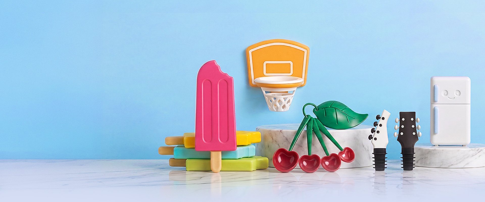 OTOTO gift-bundle characters on a light blue set: ice-pop moulds, a basketball-hoop holder, cherry measuring spoons, guitar wine stoppers and a smiling fridge