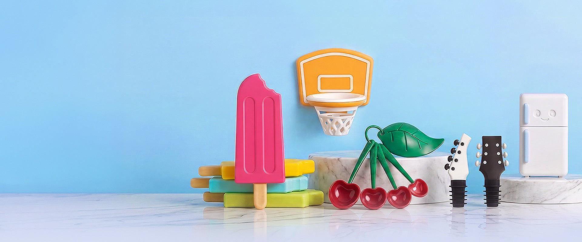 OTOTO gift-bundle characters on a light blue set: ice-pop moulds, a basketball-hoop holder, cherry measuring spoons, guitar wine stoppers and a smiling fridge
